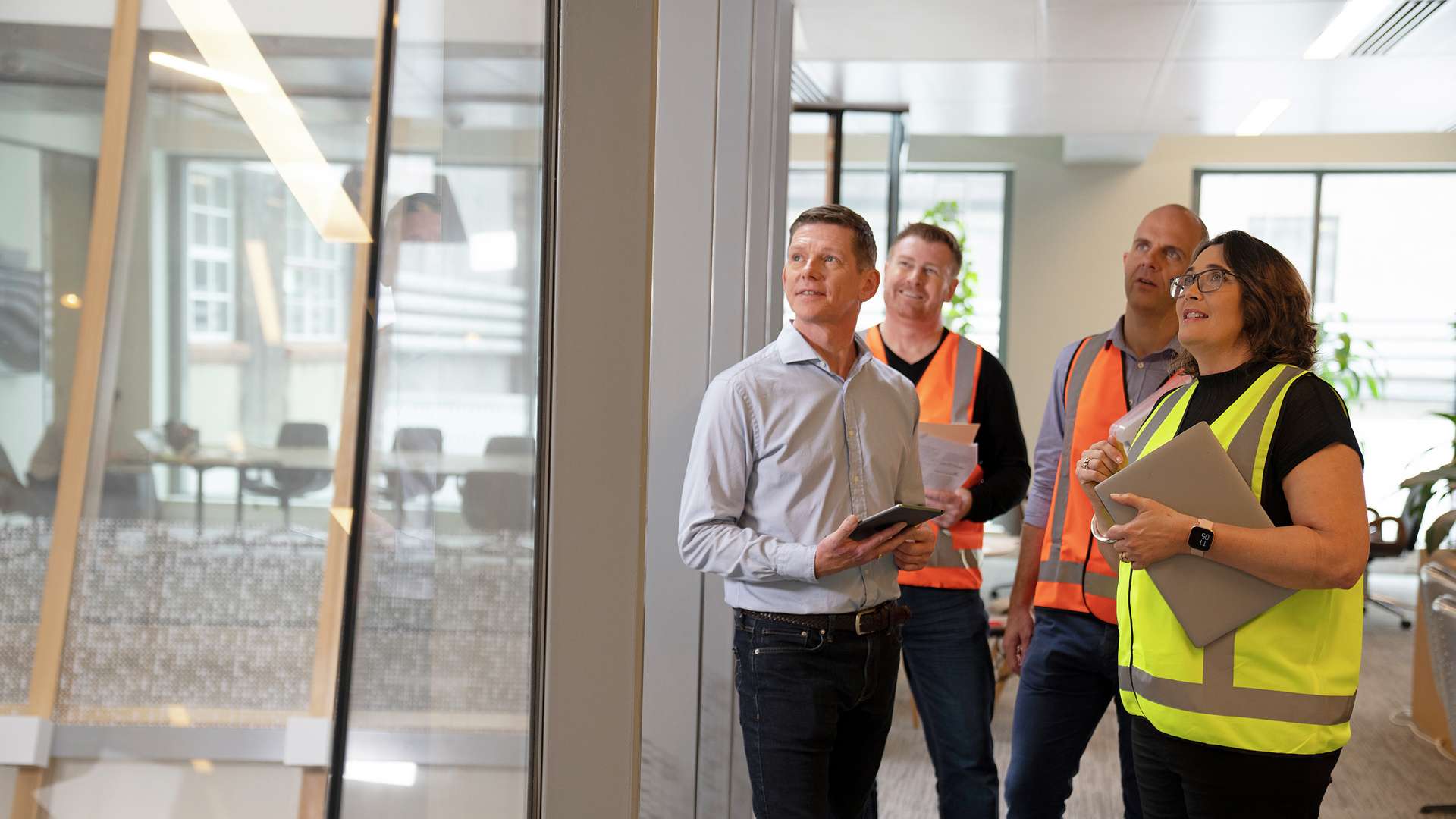 A group of CQU Asset and Maintenance Management students standing and having a discussion looking out of the office window to the worksite