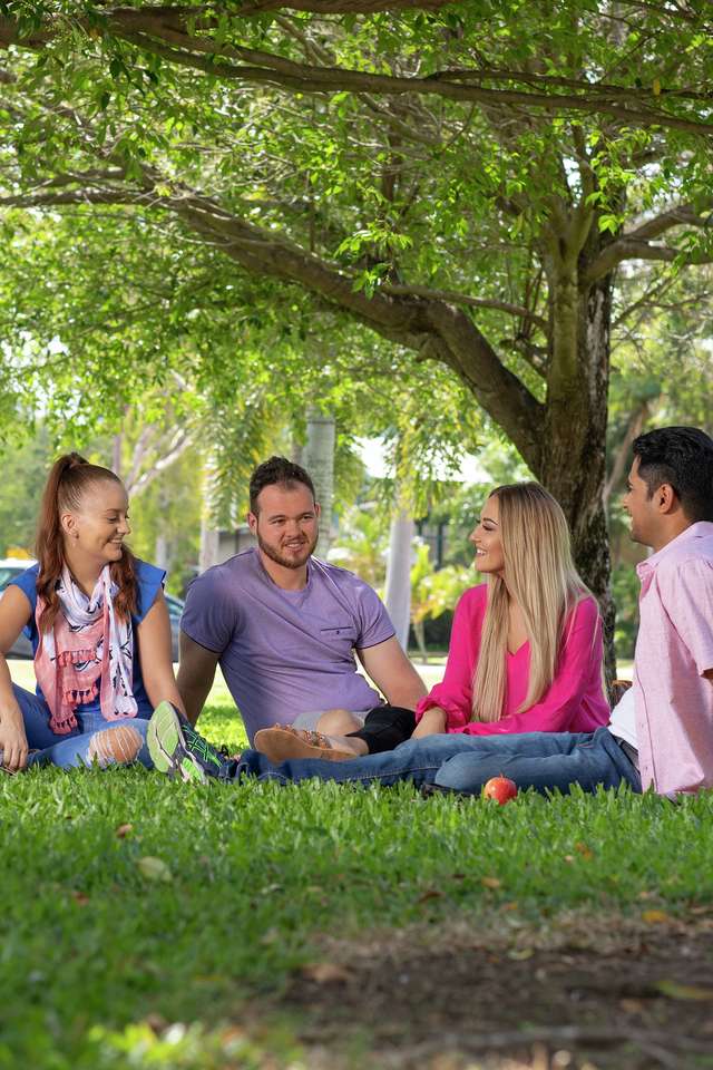 Rockhampton students sitting and chatting under the trees on campus grounds