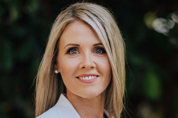 Tanya O'Shea smiling whilst wearing blue top and white suit coat