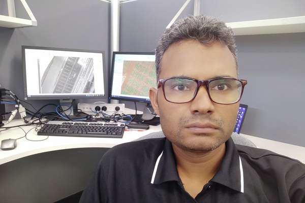 Tej Shahi sitting in a office cubicle with a computer set up
