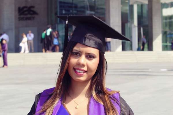 Thilini Wasana Dissanayaka in graduation regalia standing in front of the International Convention Centre Sydney