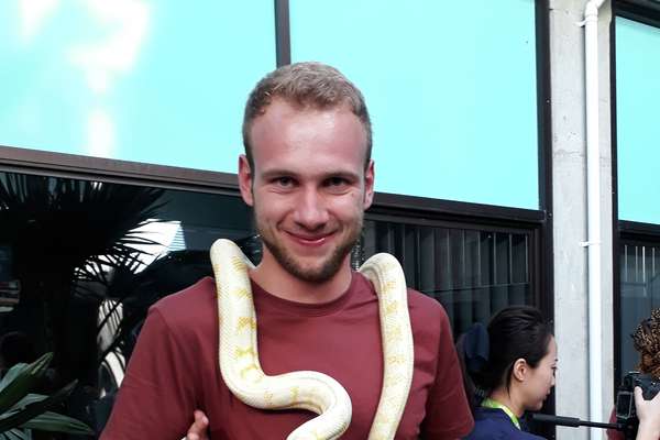Thomas Wolfsgruber, indoors, with a white and yellow snake around his neck