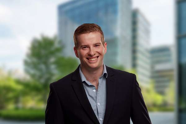Tim Bischof smiling at the camera with a cityscape in the background