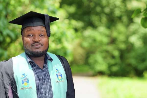 Tinashe Paul Songore standing in a park in their graduation regalia