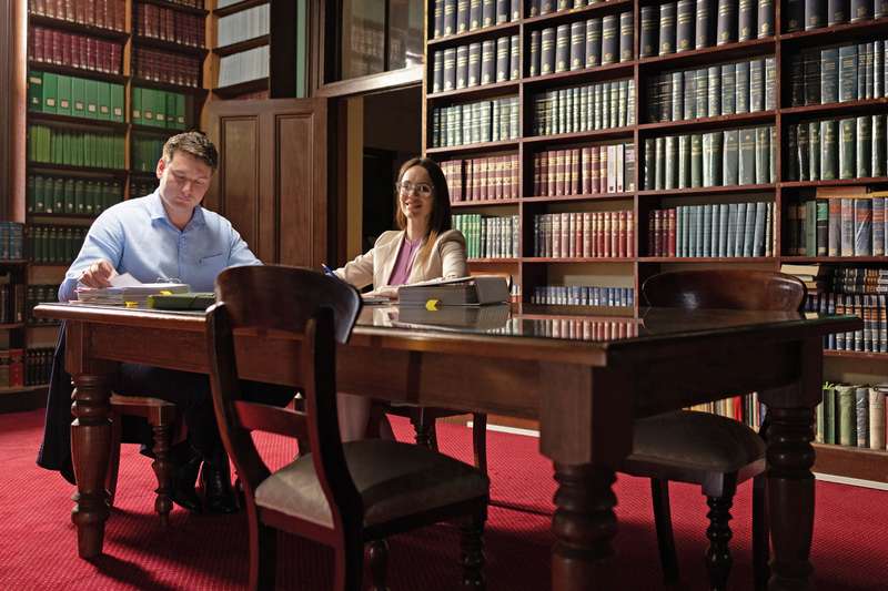 Two law students studying in a library at a long wooden table