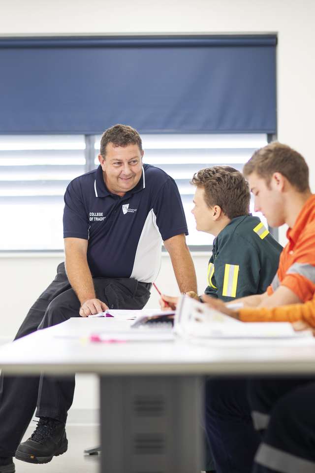 Trades teacher helping students with their work in a classroom