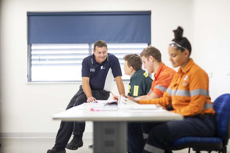 Trades teacher helping students with their work in a classroom