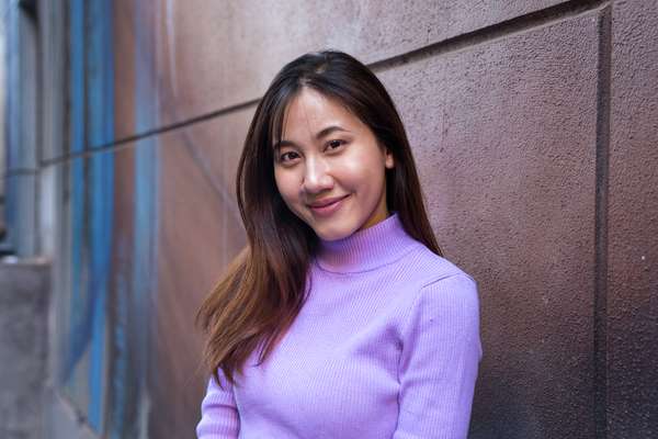 Cambodian, Masters Student Vorleak Ban smiling in front of a concrete wall