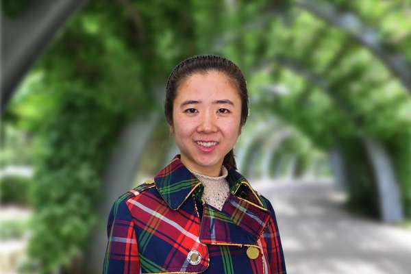 Xingyan Yang standing in a vine covered walkway