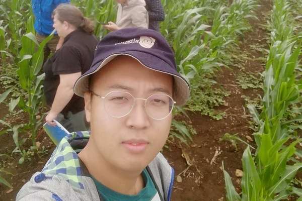 Chinese student, Xinhan Yang, in a crop field with four people behind him