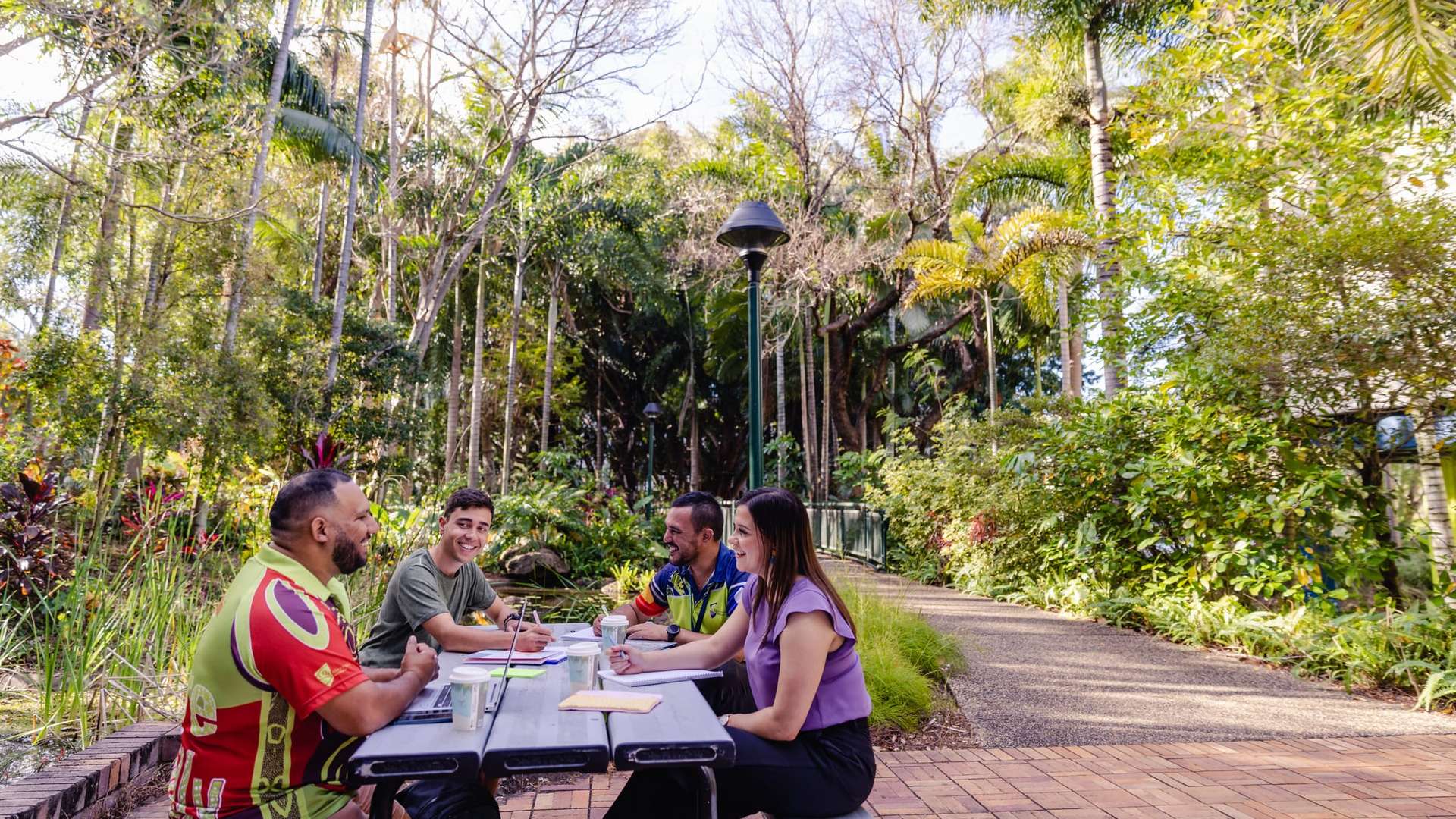 Group of people sitting at table surrounded by greenery